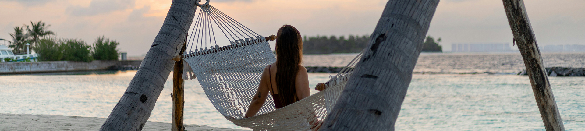 Woman sitting in a hammock overlooking the ocean at dusk in the Caribbean