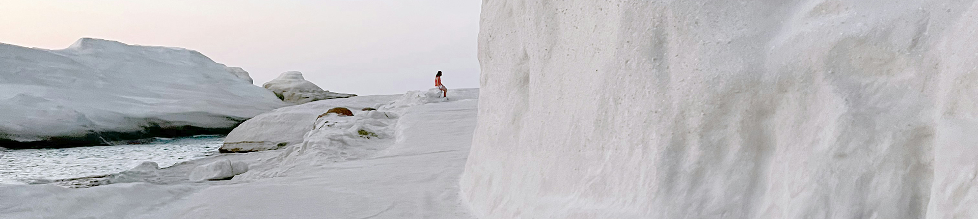 Person standing on top of a white sand hill in Milos, Greece