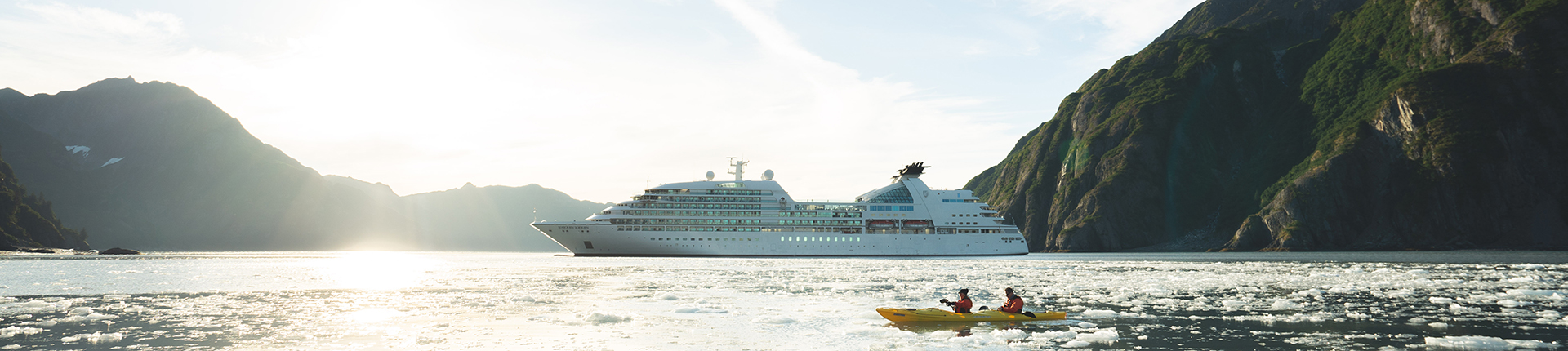 Two people kayaking in Alaska with a Seabourn ship in the background