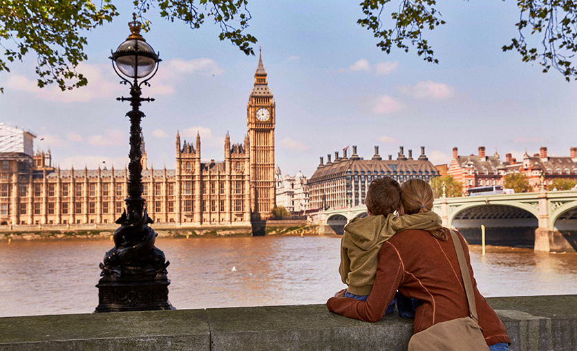 Mother with small child sitting on a cement wall looking out at Big Ben in London, England.