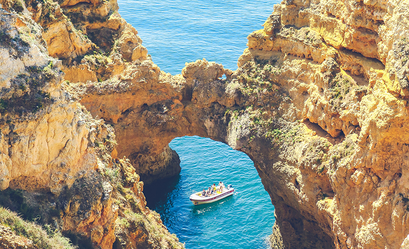 Boat along the coast of Porgual, framed by the rugged coastline.